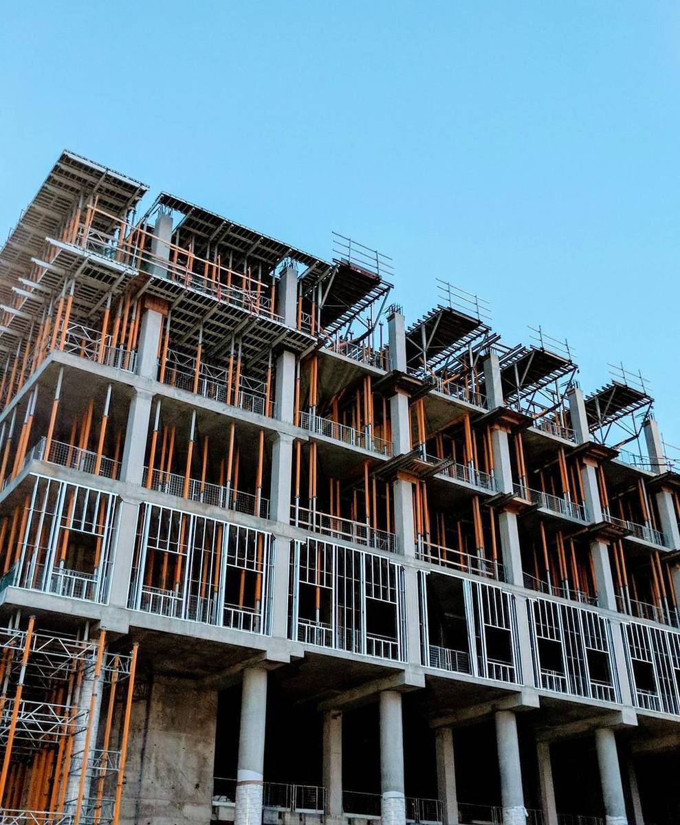 A mid-rise commercial building under construction, frame and decks exposed